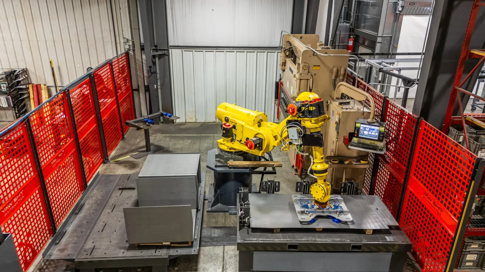 FANUC robot with a vacuum end effector tending a press brake inside TWA's red-fenced cell