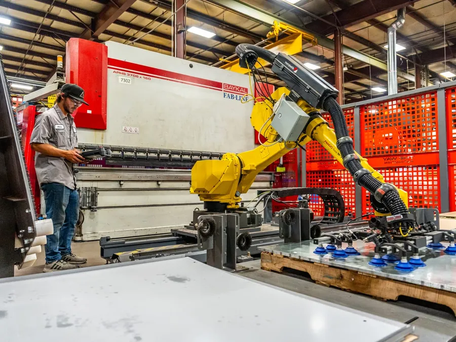 A TWA technician at the teach pendant beside the robot on its rail