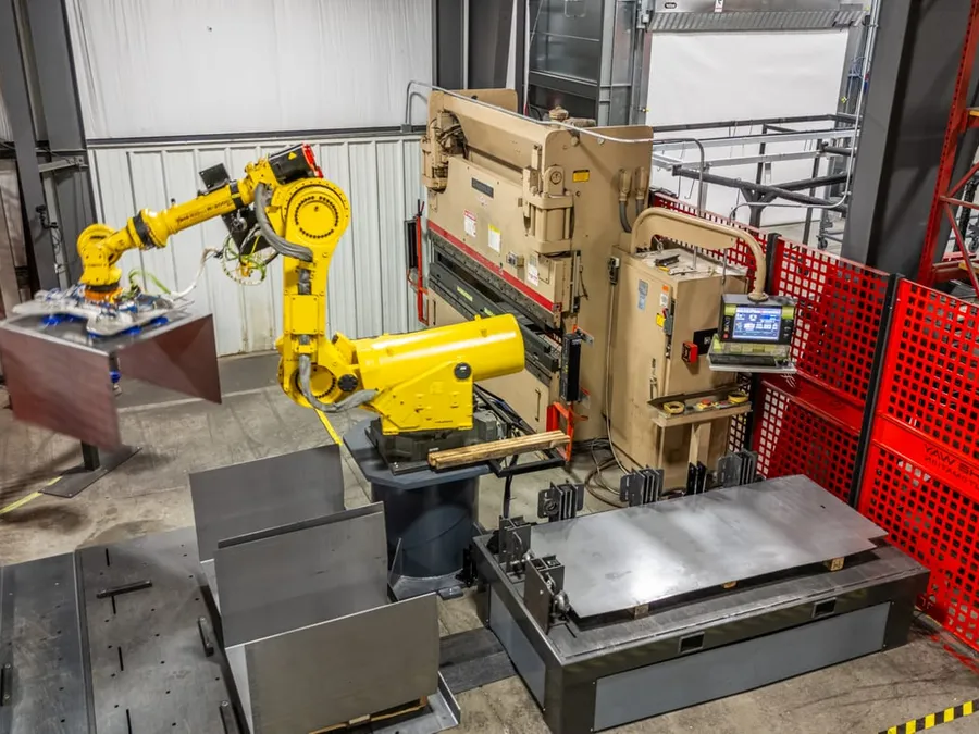The robot presenting a blank to the Cincinnati brake, formed parts stacked in the foreground